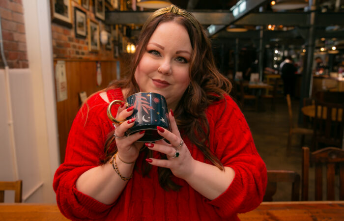 Women smiling in a red jumper creating a heart with her hands